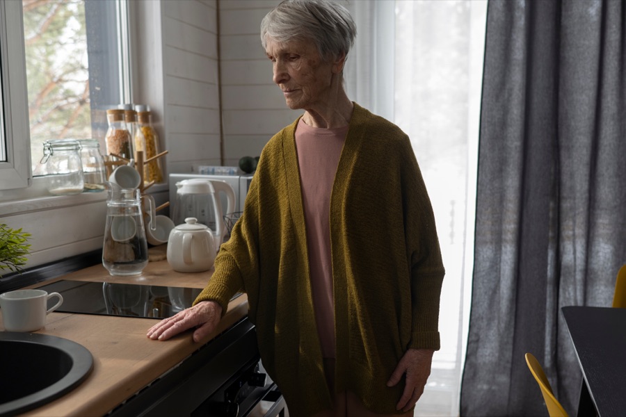 A senior standing at the counter of a home kitchen