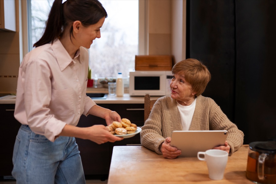 A caregiver sitting and sharing a meal with a senior at a table