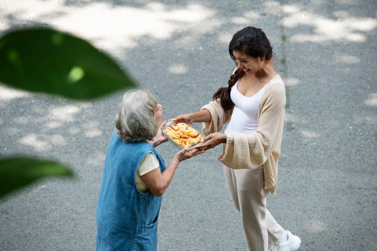 Volunteer handing a packaged meal to a senior client.