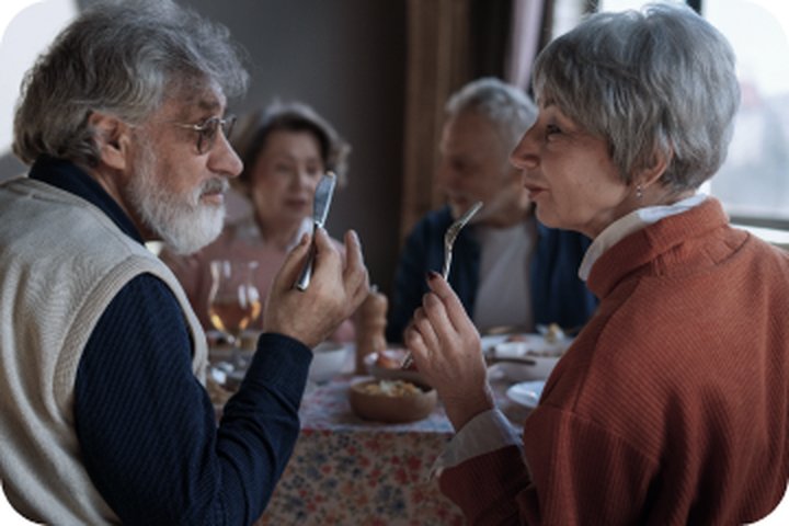 Seniors sharing a meal and conversation at a community dining site.