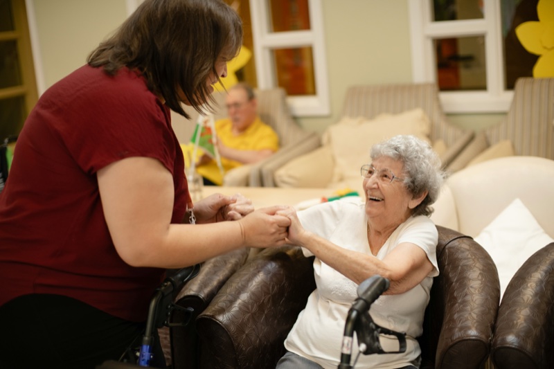 A volunteer holding hands with a senior client during a friendly visit.
