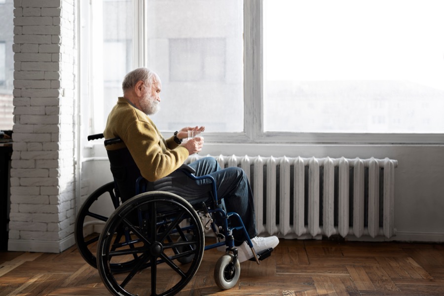 An older man using a wheelchair beside a sunlit window